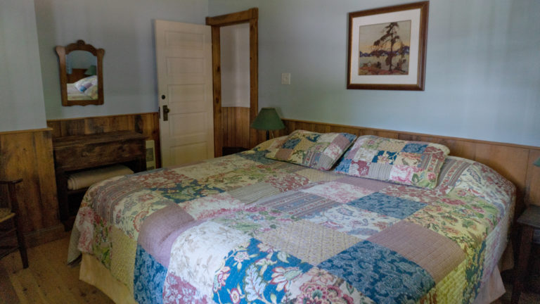 large bed covered in a patch work quilt inside a blue and wood paneled room
