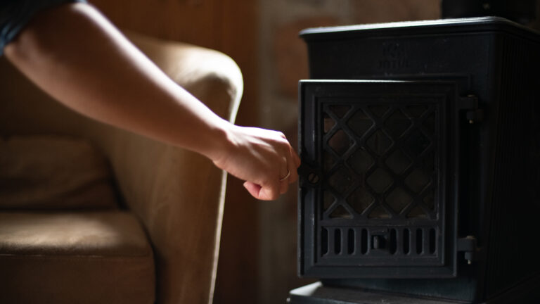a hand closing the door of a black iron fireplace
