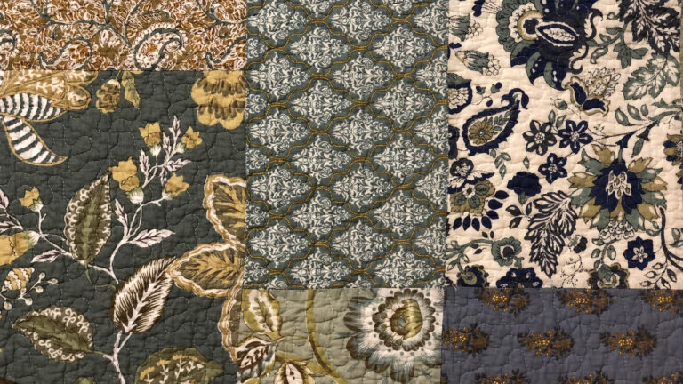 vintage block-pattern quilt with a series of floral patterns in a teal, cream and navy colour palette