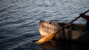 front end of a Bartlett Lodge canoe with a paddle in the water